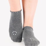 Close up photo of a woman's feet wearing grey socks with a happy face on the top of the foot