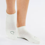 Women wearing white grip socks with green smiley face for Pilates, Barre, Yoga, and beyond.