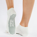 Women wearing white grip socks with green smiley face for Pilates, Barre, Yoga, and beyond.