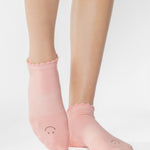 Women wearing pink coral grip socks with brown smiley face for Pilates, Barre, Yoga, and beyond. 