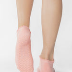 Women wearing pink coral grip socks with brown smiley face for Pilates, Barre, Yoga, and beyond. 