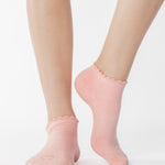Women wearing pink coral grip socks with brown smiley face for Pilates, Barre, Yoga, and beyond. 
