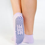 Women wearing lavender grip socks with white purple face for Pilates, Barre, Yoga, and beyond. 