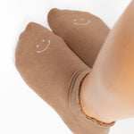 Women wearing brown beige grip socks with white smiley face for Pilates, Barre, Yoga, and beyond. 