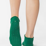 Women wearing green yellow grip socks with white face for Pilates, Barre, Yoga, and beyond. 