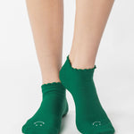 Women wearing green yellow grip socks with white face for Pilates, Barre, Yoga, and beyond. 