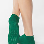 Women wearing green yellow grip socks with white face for Pilates, Barre, Yoga, and beyond. 