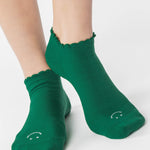 Women wearing green yellow grip socks with white face for Pilates, Barre, Yoga, and beyond. 