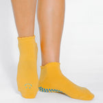 Women wearing yellow grip socks with blue purple face for Pilates, Barre, Yoga, and beyond. 