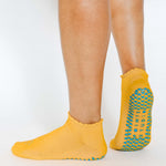 Women wearing yellow grip socks with blue purple face for Pilates, Barre, Yoga, and beyond. 
