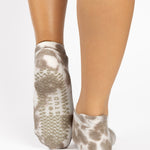 Woman wearing a tan full foot grip sock with it tie dyed brown, made for pilates, barre, yoga, and beyond.  