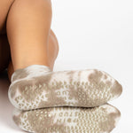 Woman wearing a tan full foot grip sock with it tie dyed brown, made for pilates, barre, yoga, and beyond.  
