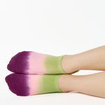 Women wearing a green, pink, and purple ombre full foot grip sock made for pilates, yoga, barre, and beyond.