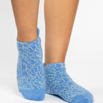 Woman wearing a light blue full foot grip sock with white squiggly lines, made for pilates, barre, yoga, and beyond.  