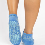Woman wearing a light blue full foot grip sock with white squiggly lines, made for pilates, barre, yoga, and beyond.  
