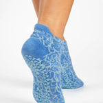 Woman wearing a light blue full foot grip sock with white squiggly lines, made for pilates, barre, yoga, and beyond.  