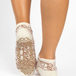 Woman wearing a tan full foot grip sock with brown squiggly lines, made for pilates, barre, yoga, and beyond.  