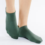 Women wearing a solid sage green full foot grip sock made for Pilates, Barre, Yoga, and beyond. 