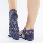 Womean wearing an amethyst purple grip socks with white squiguilly lines. Made for pilates, barre, yoga, and beyond. 