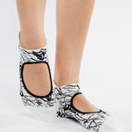 Womean wearing a white strap grip socks with black squiguilly lines. Made for pilates, barre, yoga, and beyond. 