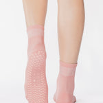 Women wearing a solid coral pink ankle grip sock made for Pilates, Barre, Yoga, and beyond. 