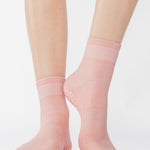 Women wearing a solid coral pink ankle grip sock made for Pilates, Barre, Yoga, and beyond. 