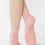 Women wearing a solid coral pink ankle grip sock made for Pilates, Barre, Yoga, and beyond. 