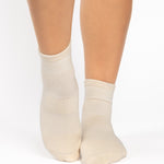 Women wearing a solid off white ankle grip sock made for Pilates, Barre, Yoga, and beyond. 
