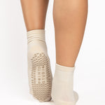 Women wearing a solid off white ankle grip sock made for Pilates, Barre, Yoga, and beyond. 