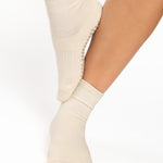 Women wearing a solid off white ankle grip sock made for Pilates, Barre, Yoga, and beyond. 