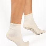 Women wearing a solid off white ankle grip sock made for Pilates, Barre, Yoga, and beyond. 