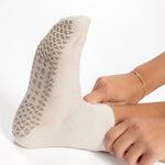 Women wearing a solid off white ankle grip sock made for Pilates, Barre, Yoga, and beyond. 