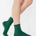 Women wearing a solid pine green ankle grip sock made for Pilates, Barre, Yoga, and beyond. 