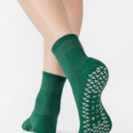 Women wearing a solid pine green ankle grip sock made for Pilates, Barre, Yoga, and beyond. 