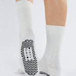 Women wearing white fuzzy plush crew grip socks with a black happy face for recovery and relaxing.  