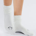 Women wearing white fuzzy plush crew grip socks with a black happy face for recovery and relaxing.  