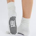 Women wearing white fuzzy plush crew grip socks with a black happy face for recovery and relaxing.  