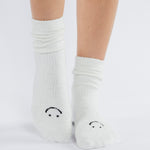 Women wearing white fuzzy plush crew grip socks with a black happy face for recovery and relaxing.  