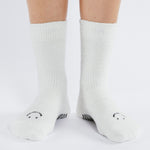 Women wearing white fuzzy plush crew grip socks with a black happy face for recovery and relaxing.  
