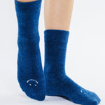 Women wearing dark blue fuzzy plush crew grip socks with a white happy face for recovery and relaxing.  
