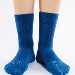 Women wearing dark blue fuzzy plush crew grip socks with a white happy face for recovery and relaxing.  