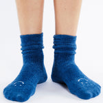 Women wearing dark blue fuzzy plush crew grip socks with a white happy face for recovery and relaxing.  