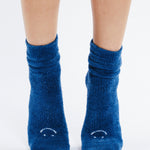 Women wearing dark blue fuzzy plush crew grip socks with a white happy face for recovery and relaxing.  