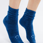Women wearing dark blue fuzzy plush crew grip socks with a white happy face for recovery and relaxing.  