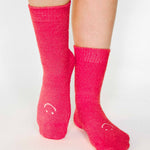 Women wearing watermelon fuzzy plush crew grip socks with a white happy face for recovery and relaxing.  