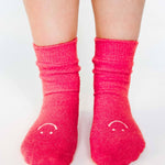 Women wearing watermelon fuzzy plush crew grip socks with a white happy face for recovery and relaxing.  