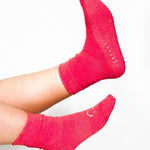 Women wearing watermelon fuzzy plush crew grip socks with a white happy face for recovery and relaxing.  