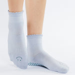 Women wearing light blue ankle grip socks with blue happy face for Pilates, Barre, Yoga, and beyond. 