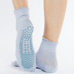 Women wearing light blue ankle grip socks with blue happy face for Pilates, Barre, Yoga, and beyond. 