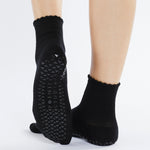 Women wearing black ankle grip socks with white happy face for Pilates, Barre, Yoga, and beyond. 